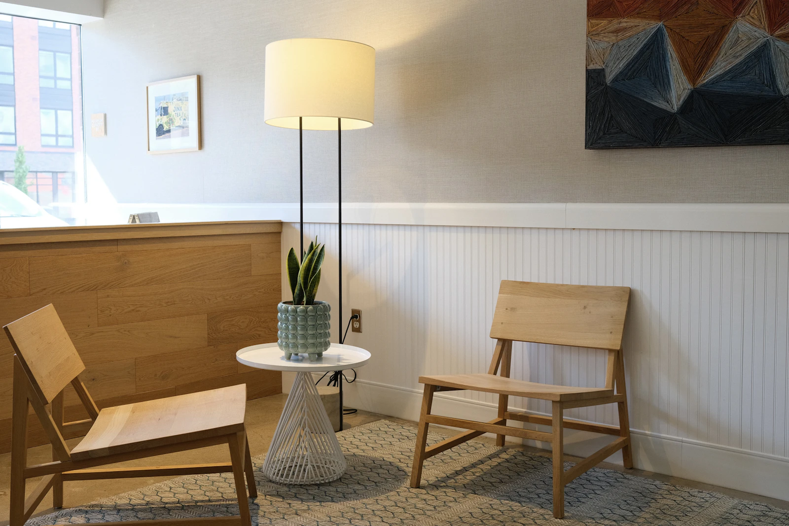 Two wooden armchairs by a window in a quiet counselling room.